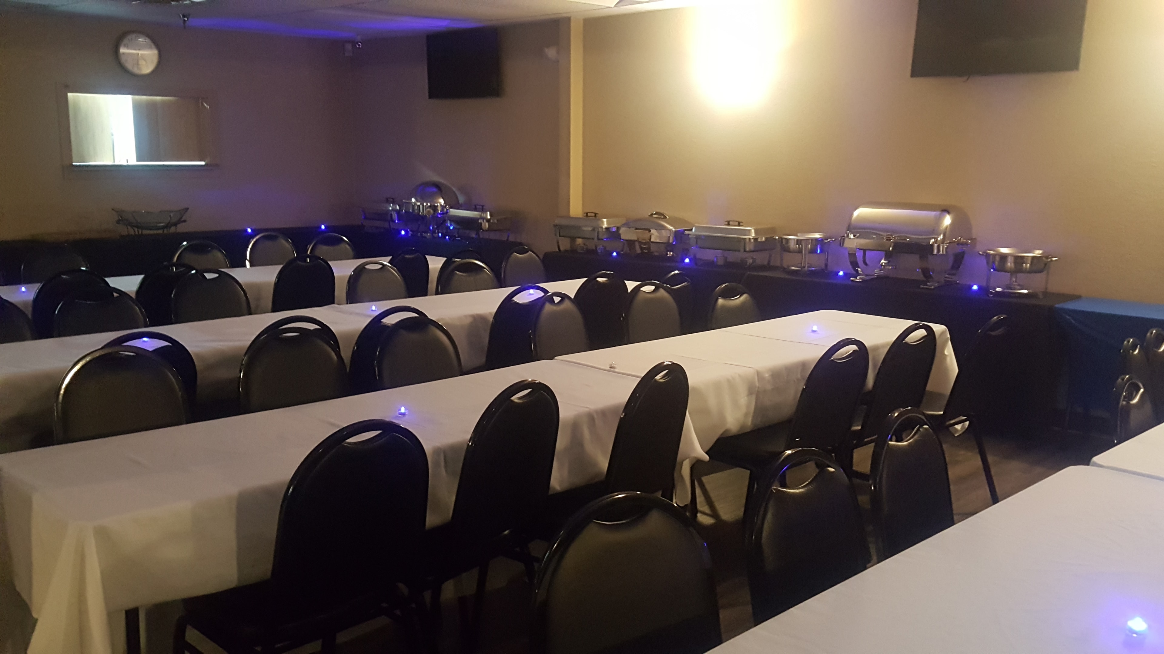 Corporate banquet room with white-clothed tables, buffet service, and blue accent lighting