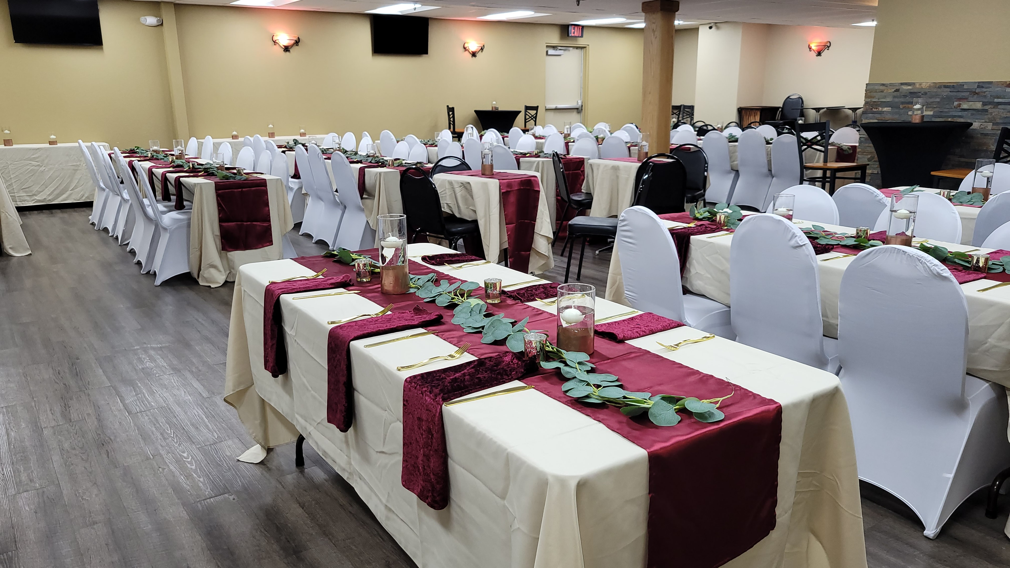 Angled view of a corporate event setup with burgundy runners and white chairs