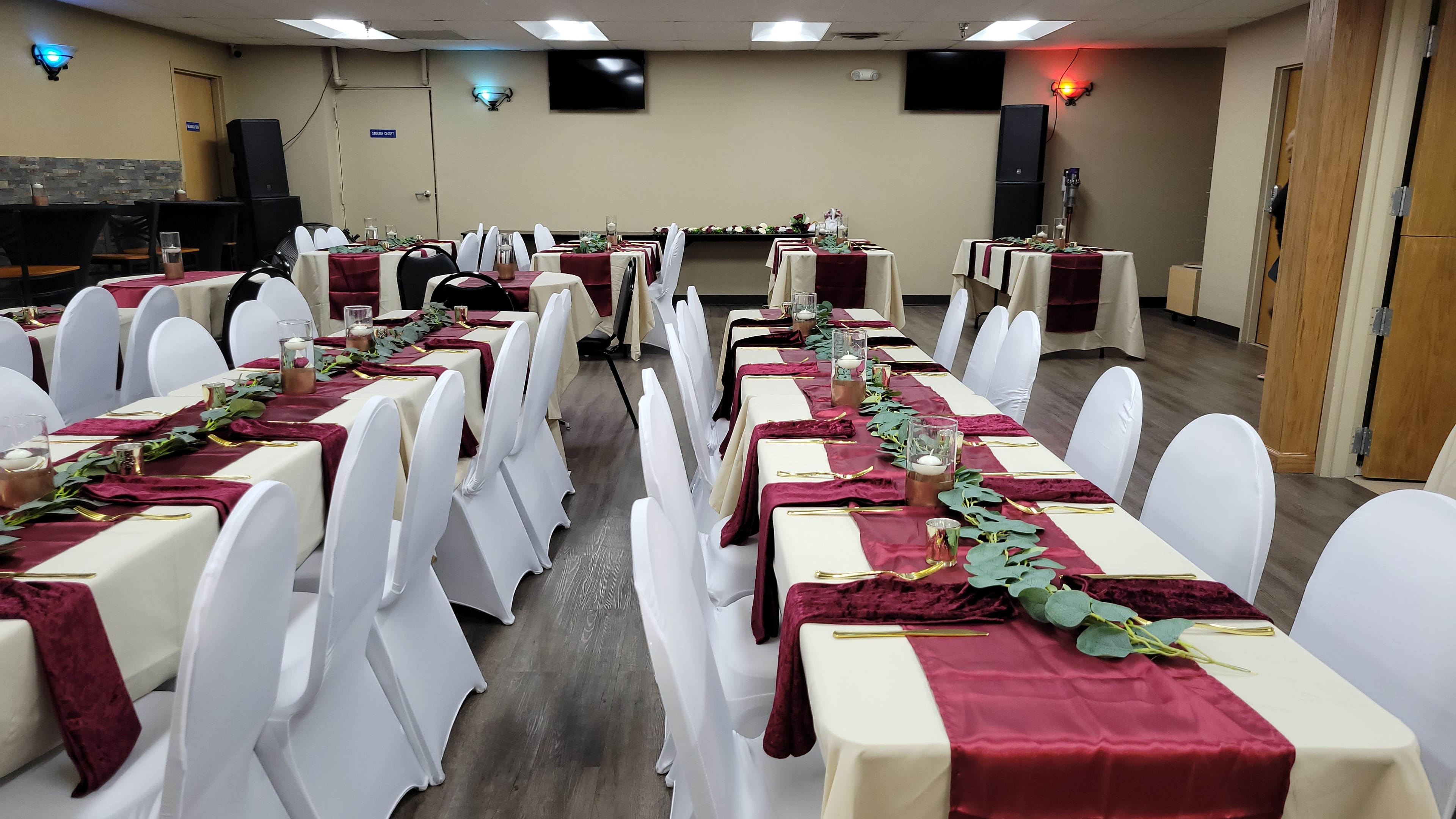 Corporate banquet room prepared with tables, greenery, and event lighting
