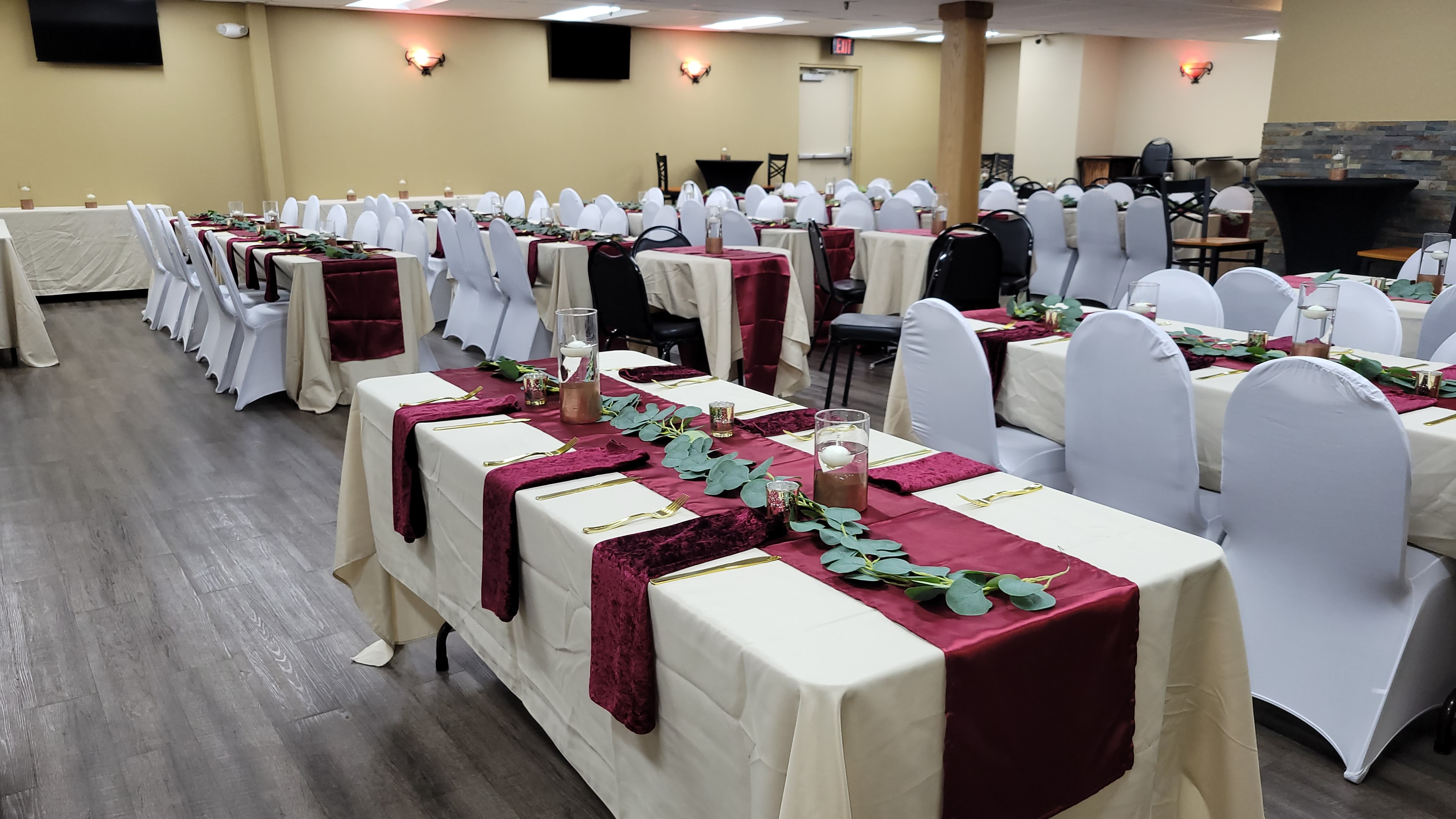 Wide view of a corporate banquet room with burgundy table settings