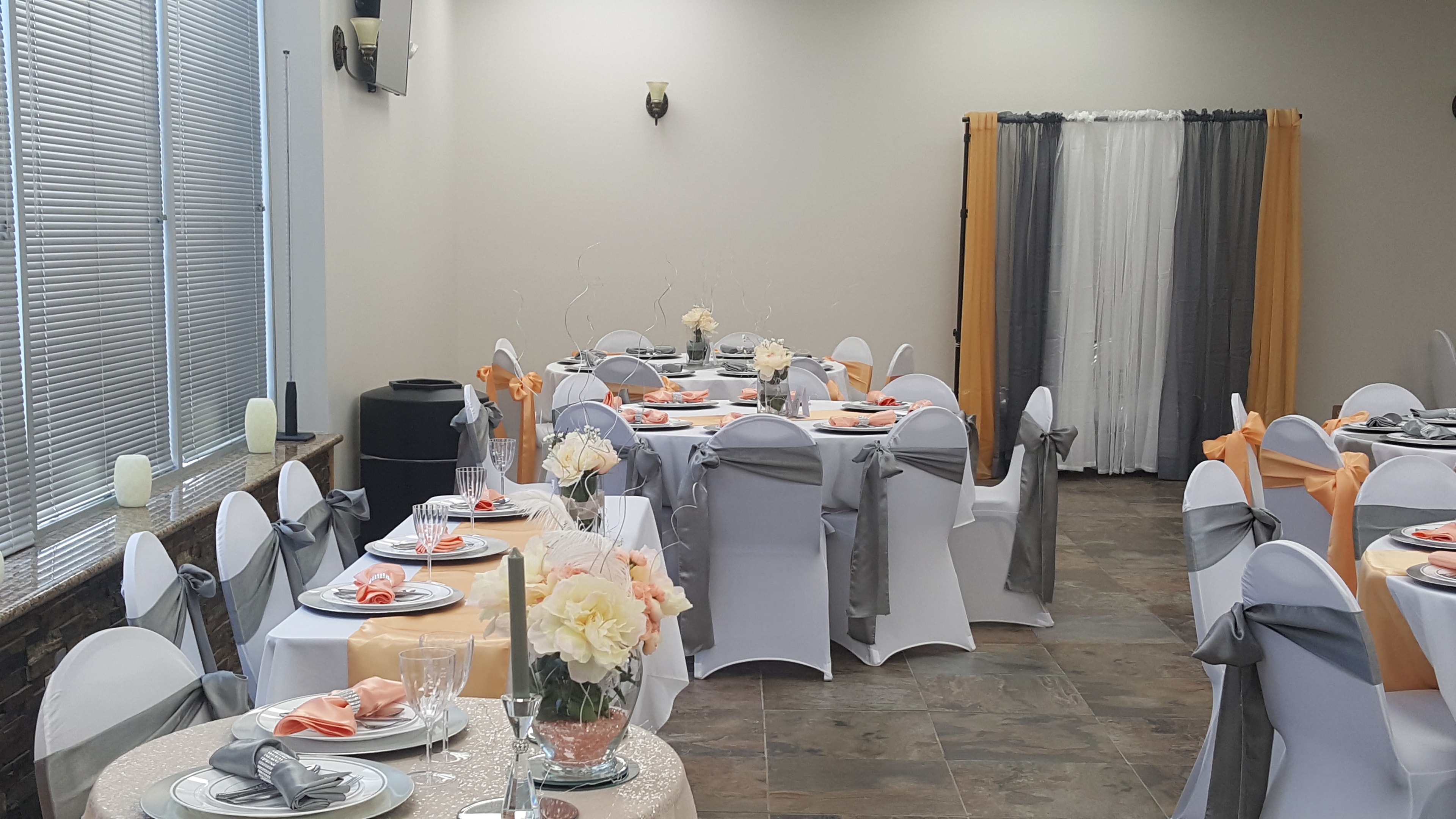 Decorated dining room with peach and gray reception tables at Deja Vu Event Space